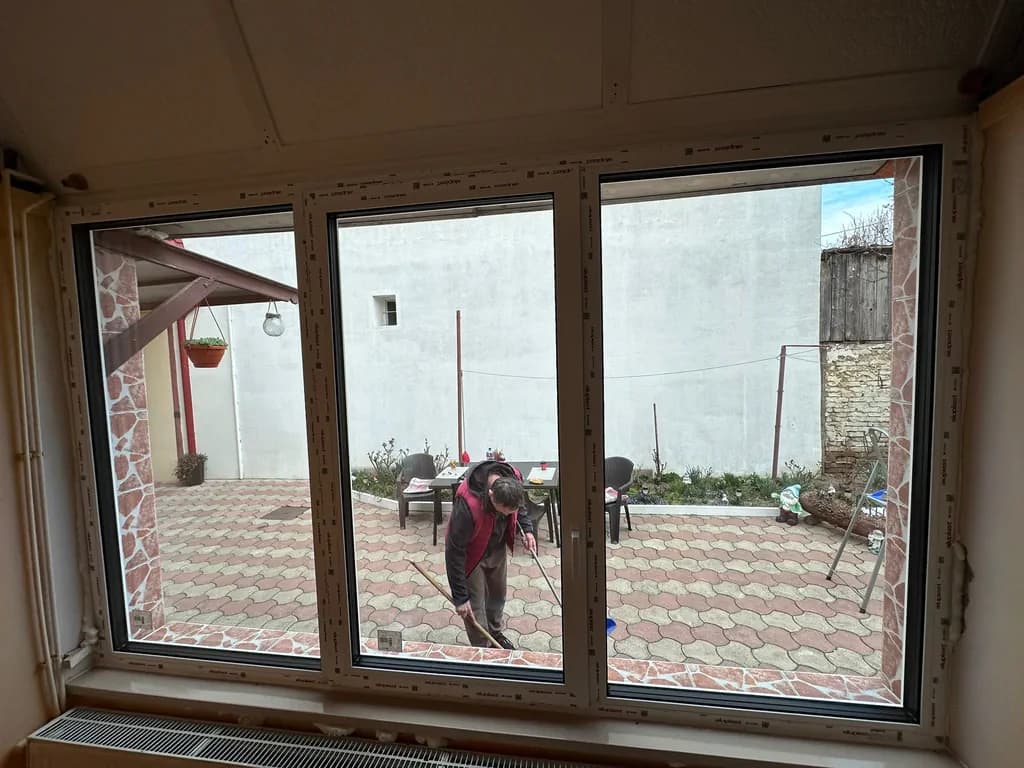 Trei panouri mari de ferestre PVC orientate spre o curte residentială