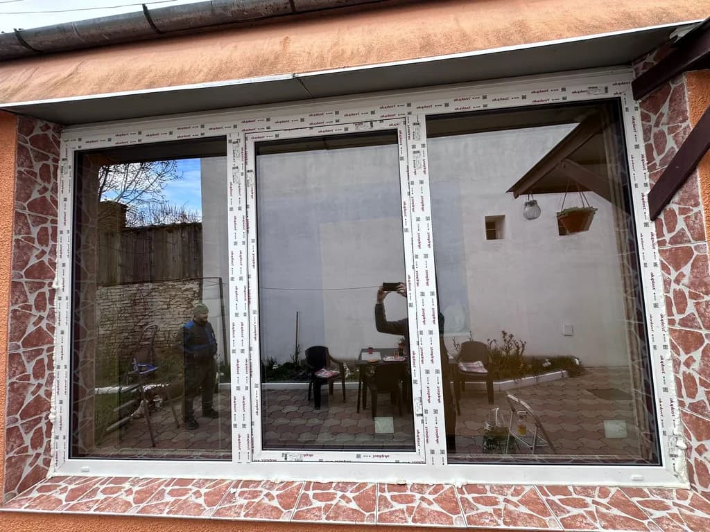 Ușă glisantă PVC cu trei panouri pe o fațadă oranj
